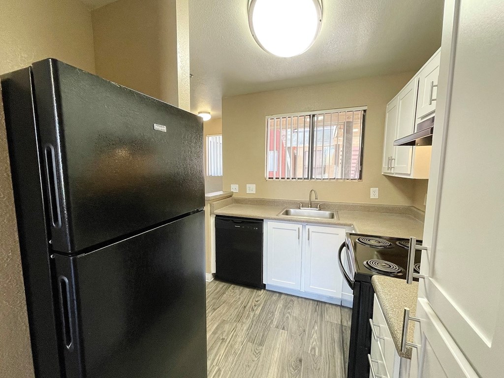 a small kitchen with white cabinets and black appliances