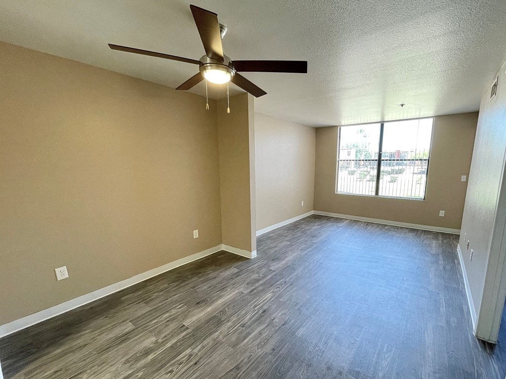 an empty living room with a ceiling fan