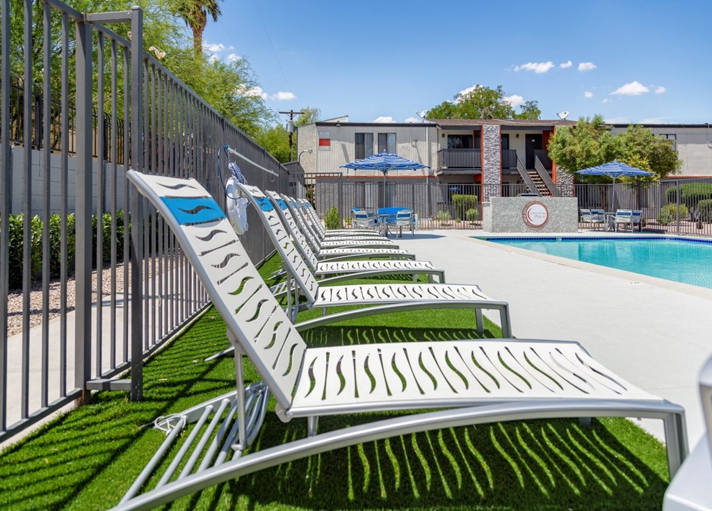 a row of white lounge chairs next to a pool