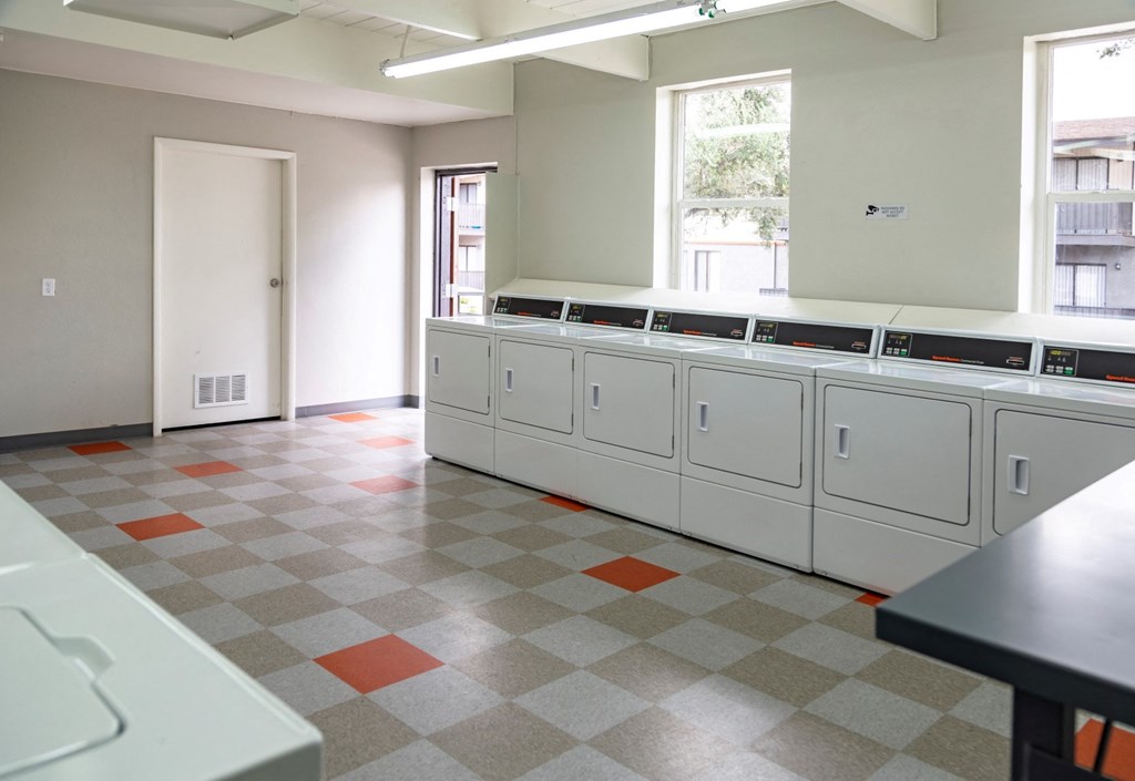 a large room with a row of washers and dryers in it