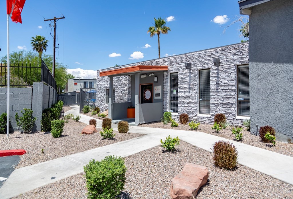 the front entrance of a building with a stone facade and a landscaped front yard