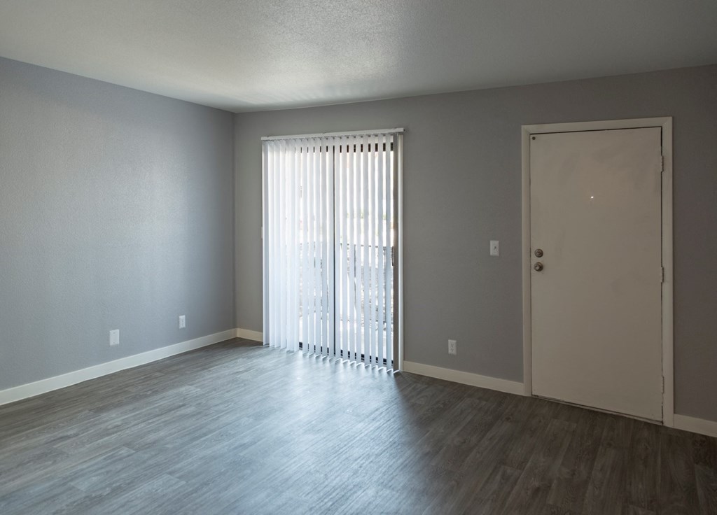 an empty living room with wood floors and a sliding glass door