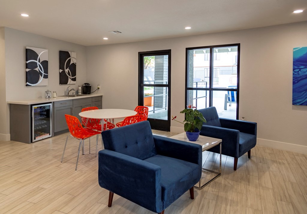 a living room with blue chairs and a white table and a kitchen