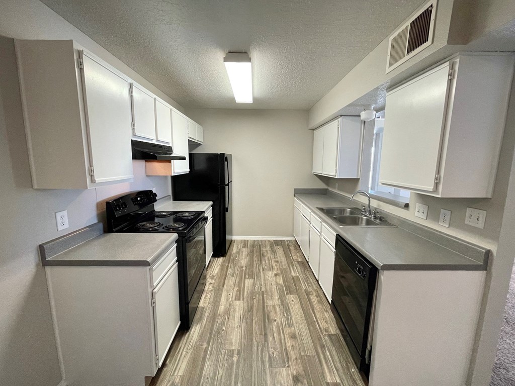 a kitchen with white cabinets and black appliances and a wood floor