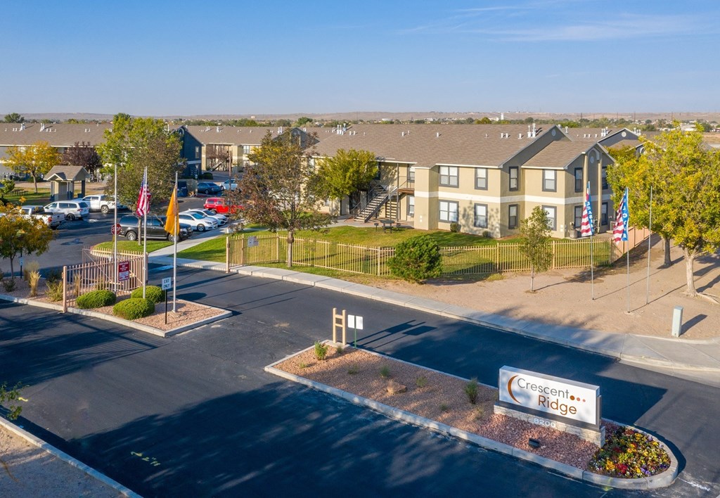an aerial view of an apartment complex with flags and a parking lot