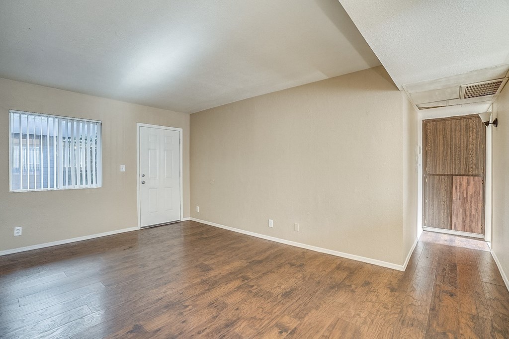 an empty living room with wood flooring and a door to a closet