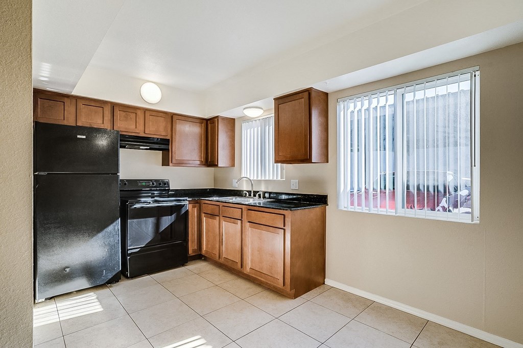 an empty kitchen with black appliances and wooden cabinets