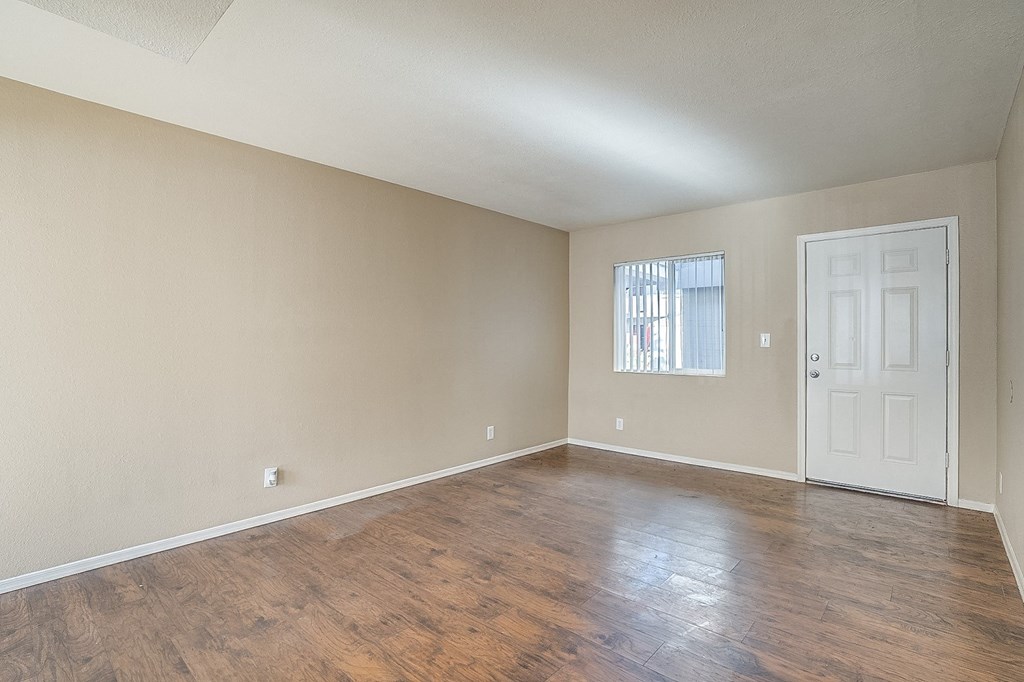 an empty living room with wood flooring and a white door