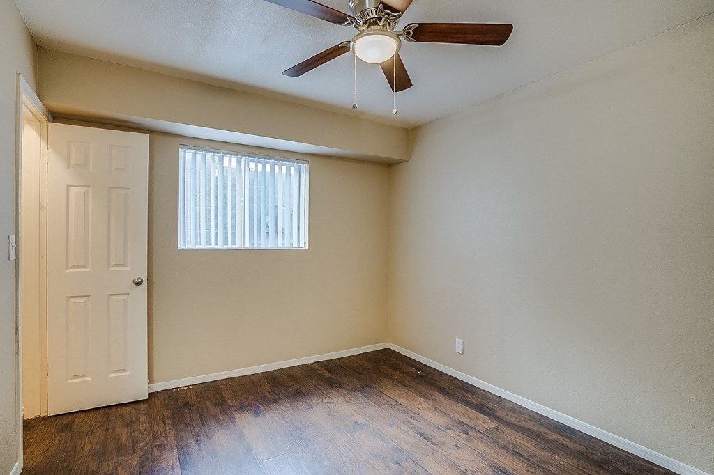 an empty living room with hard wood floors and a ceiling fan