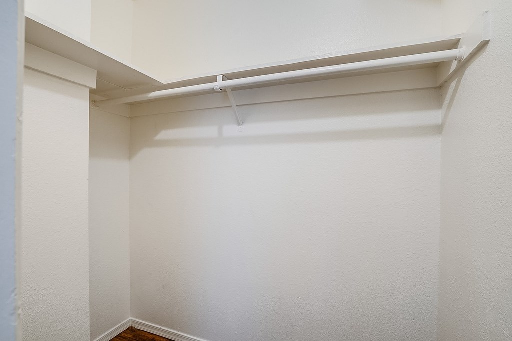 an empty closet with a white wall and a white pipe on the ceiling