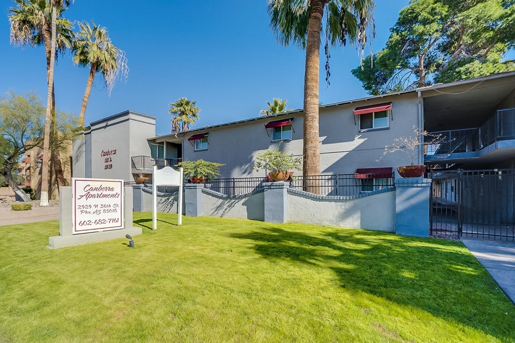 a house with a green lawn and palm trees in front of it