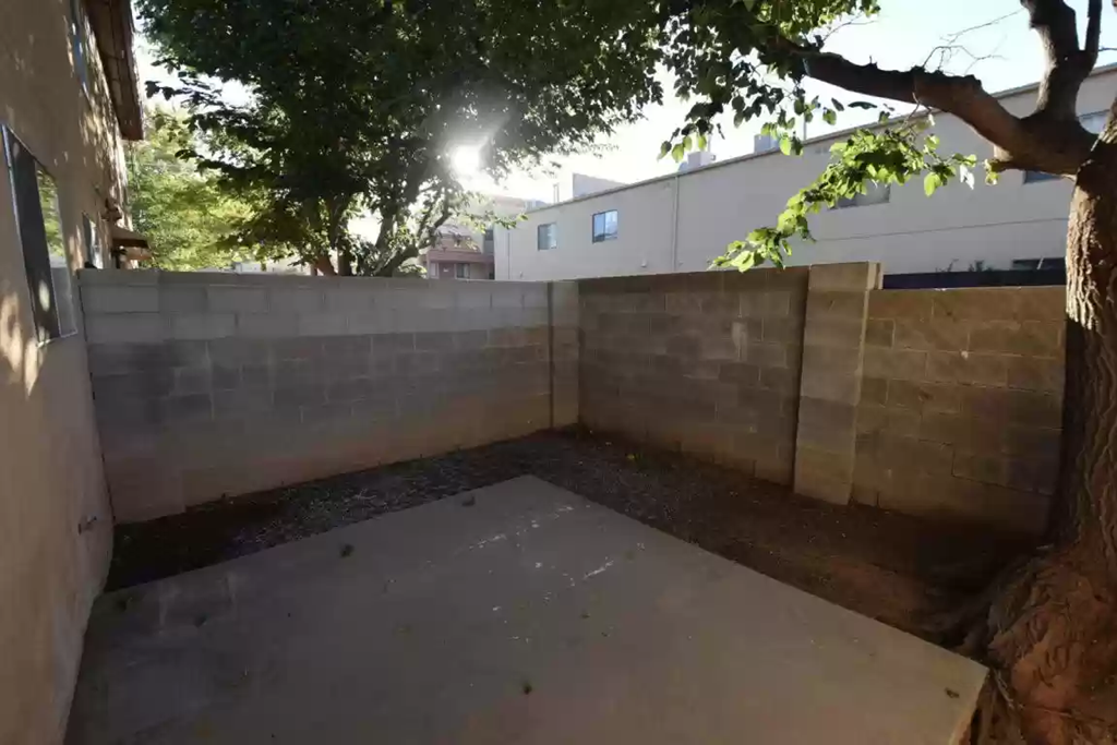 the backyard of a house with a concrete patio and a tree