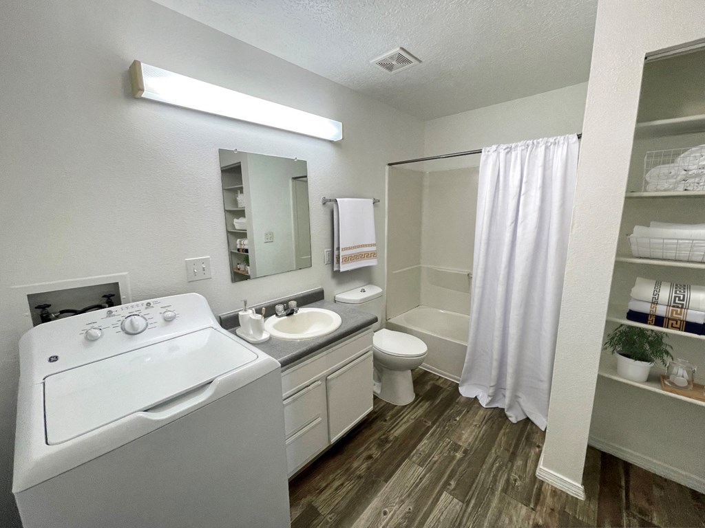 a bathroom with a washer and dryer and a sink and a toilet