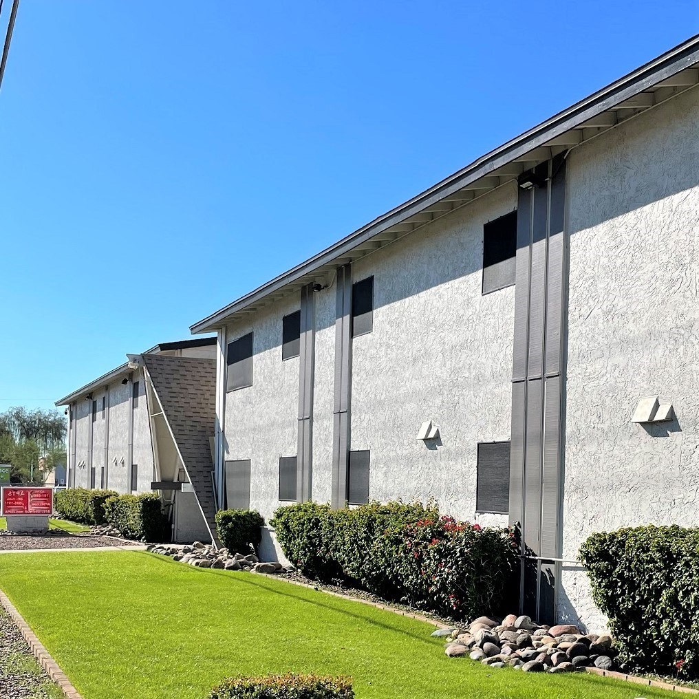 a building with a green lawn and bushes in front of it