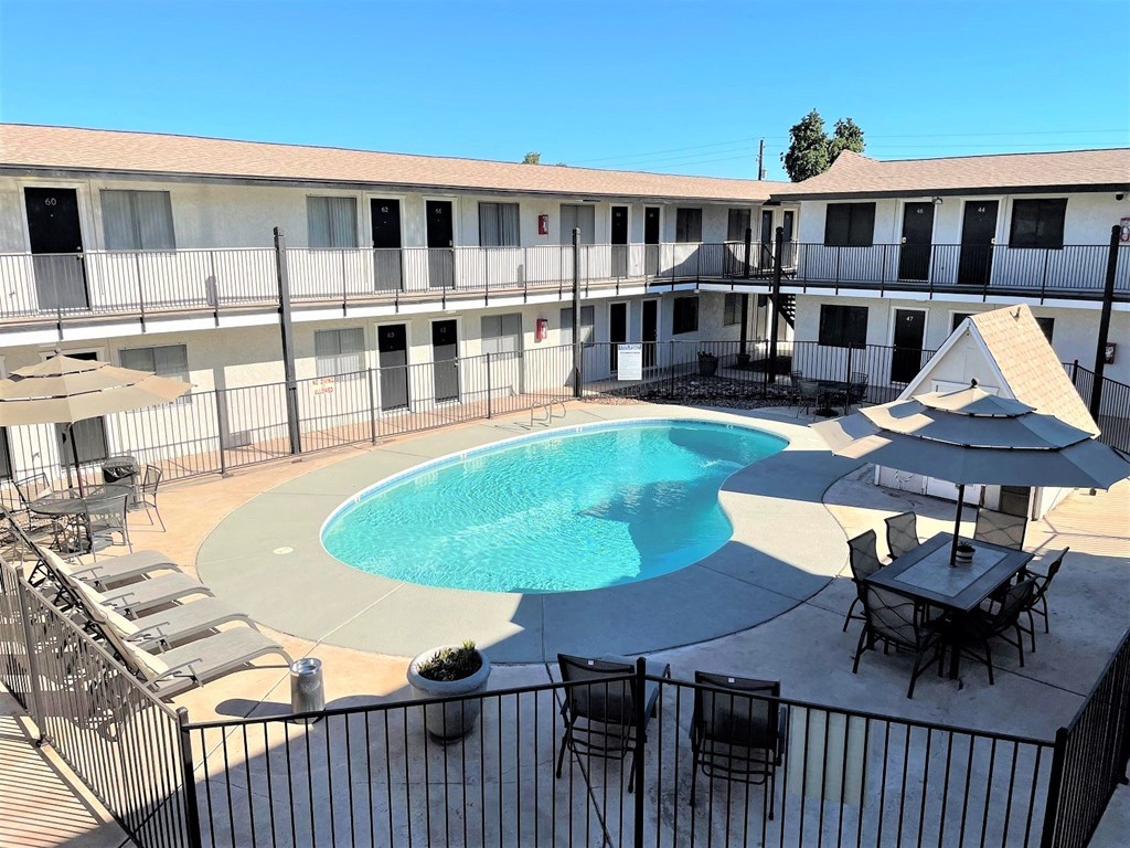 an aerial view of a swimming pool and a patio with chairs and umbrellas