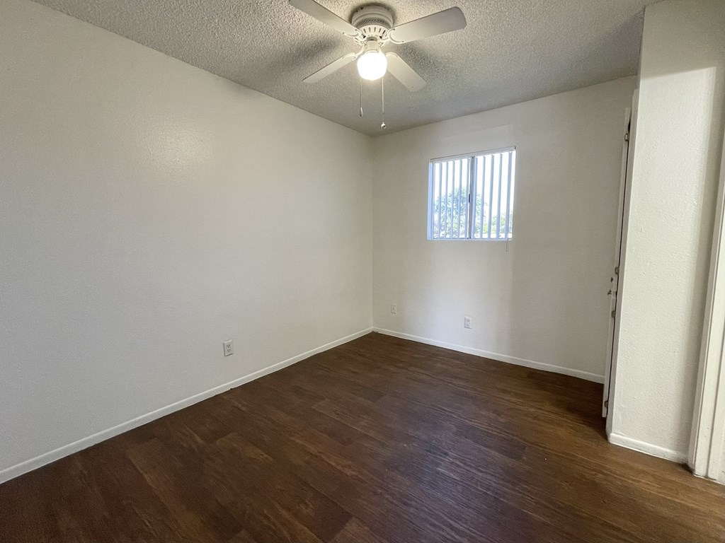 an empty living room with wood flooring and a ceiling fan