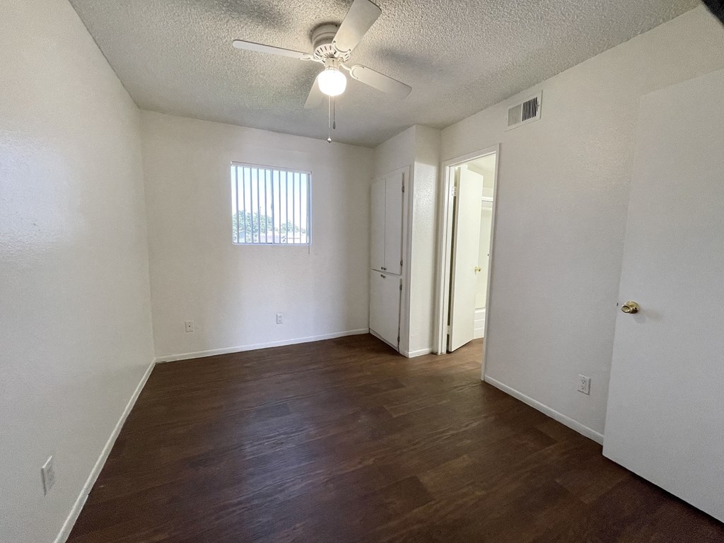 an empty living room with wood flooring and a ceiling fan