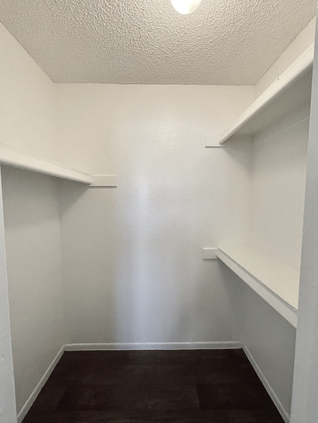 an empty room with white walls and shelves and a dark floor