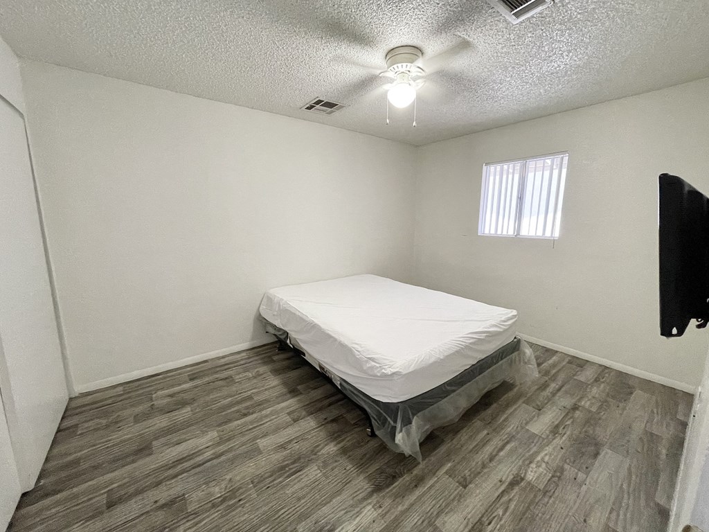 an empty bedroom with a bed and a ceiling fan