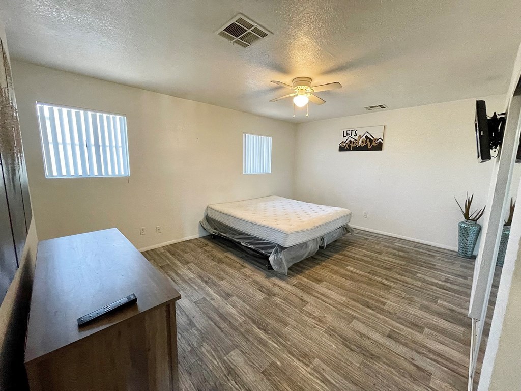 an empty bedroom with a bed and a ceiling fan