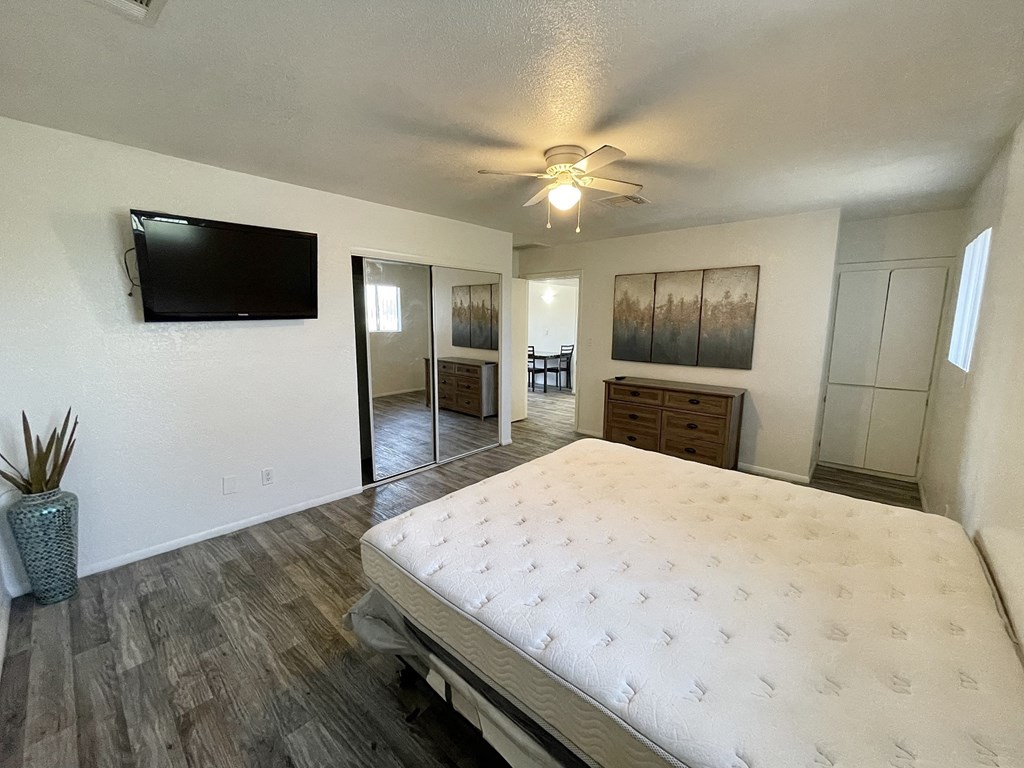 a bedroom with a bed and a ceiling fan and a tv