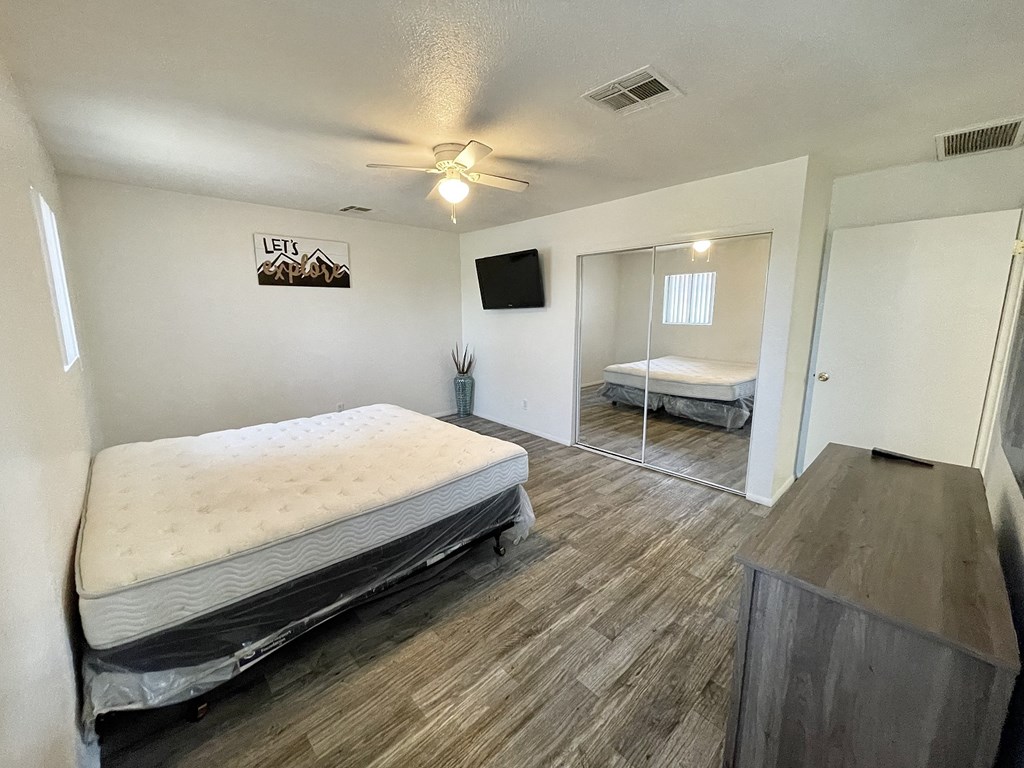an empty bedroom with two beds and a ceiling fan