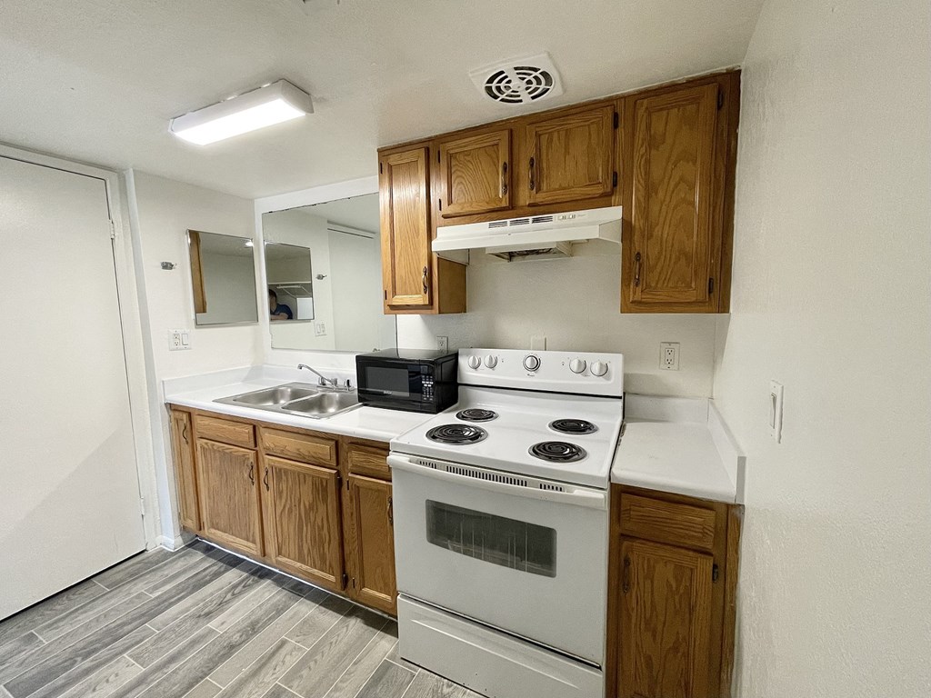 an empty kitchen with white appliances and wooden cabinets