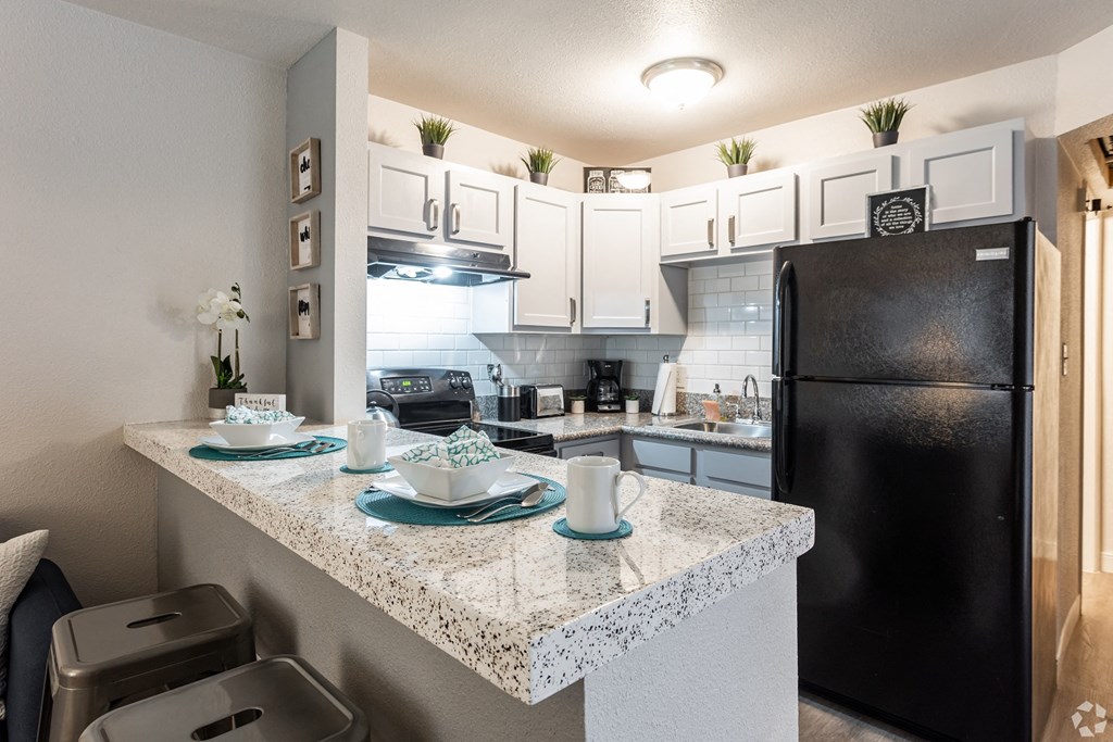 a kitchen with a granite counter top and a black refrigerator