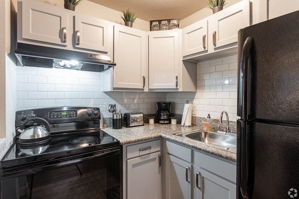 a kitchen with white cabinets and black appliances