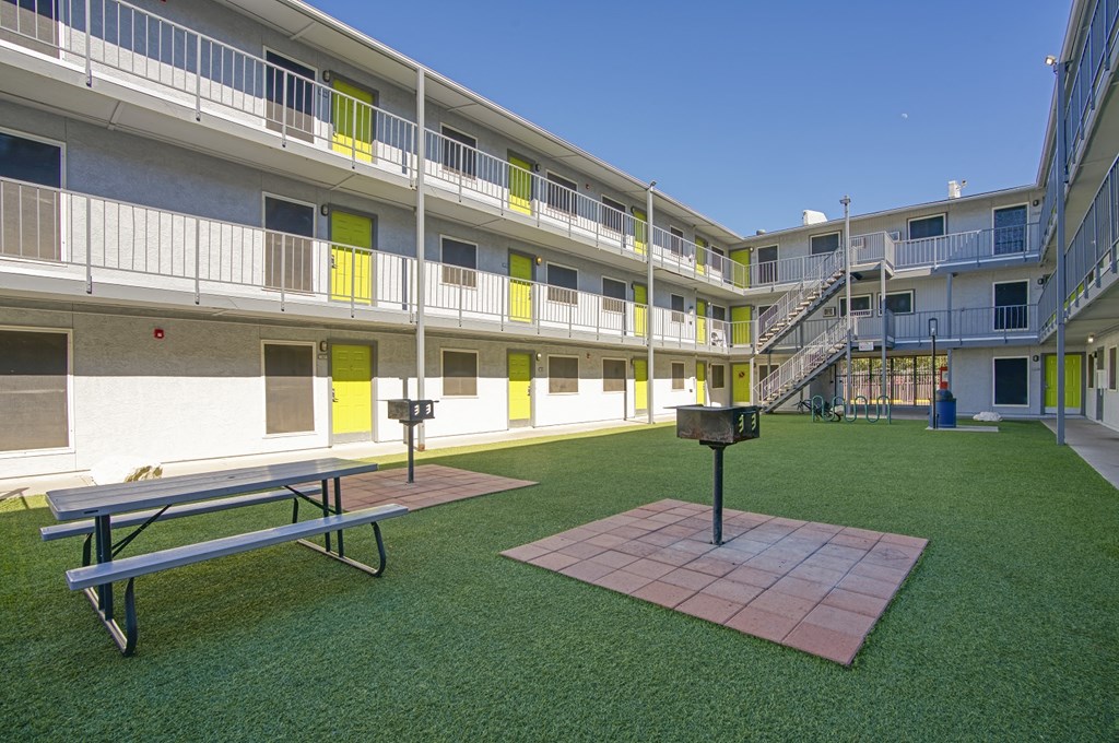 a courtyard with a picnic table and a grill in an apartment building
