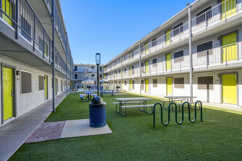 a courtyard with picnic tables and a trash can in a courtyard of an apartment building