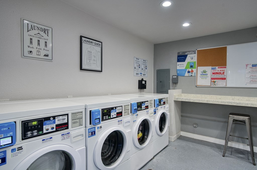 a washer and dryer in a laundry room with a counter and a chair