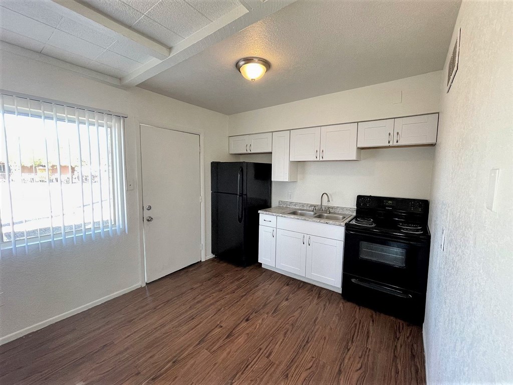 an empty kitchen with black appliances and white cabinets