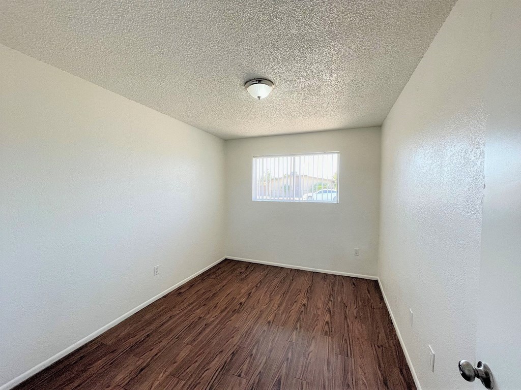 an empty room with wood flooring and a window