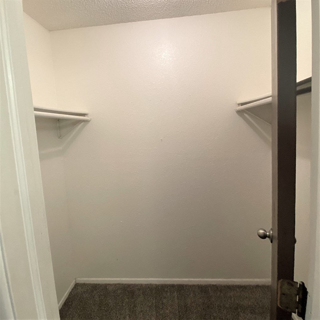 a walk in closet with two shelves and a door