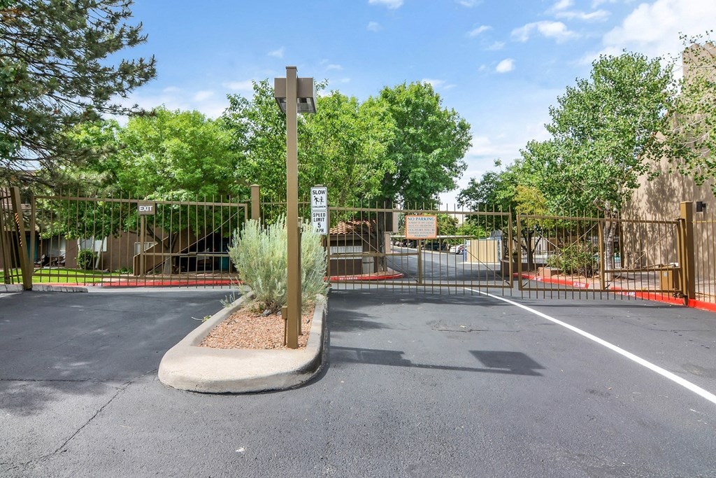 the entrance to a park with a fence and a parking lot