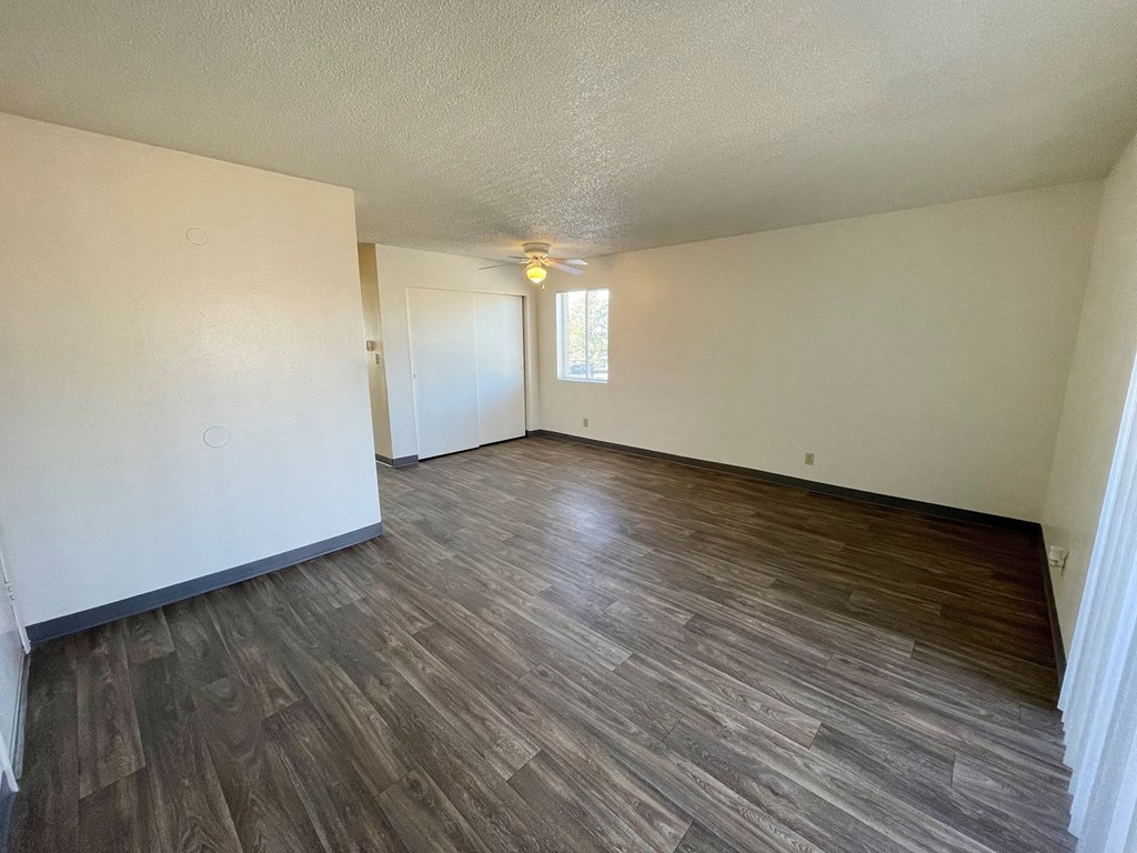 an empty living room with wood flooring and white walls