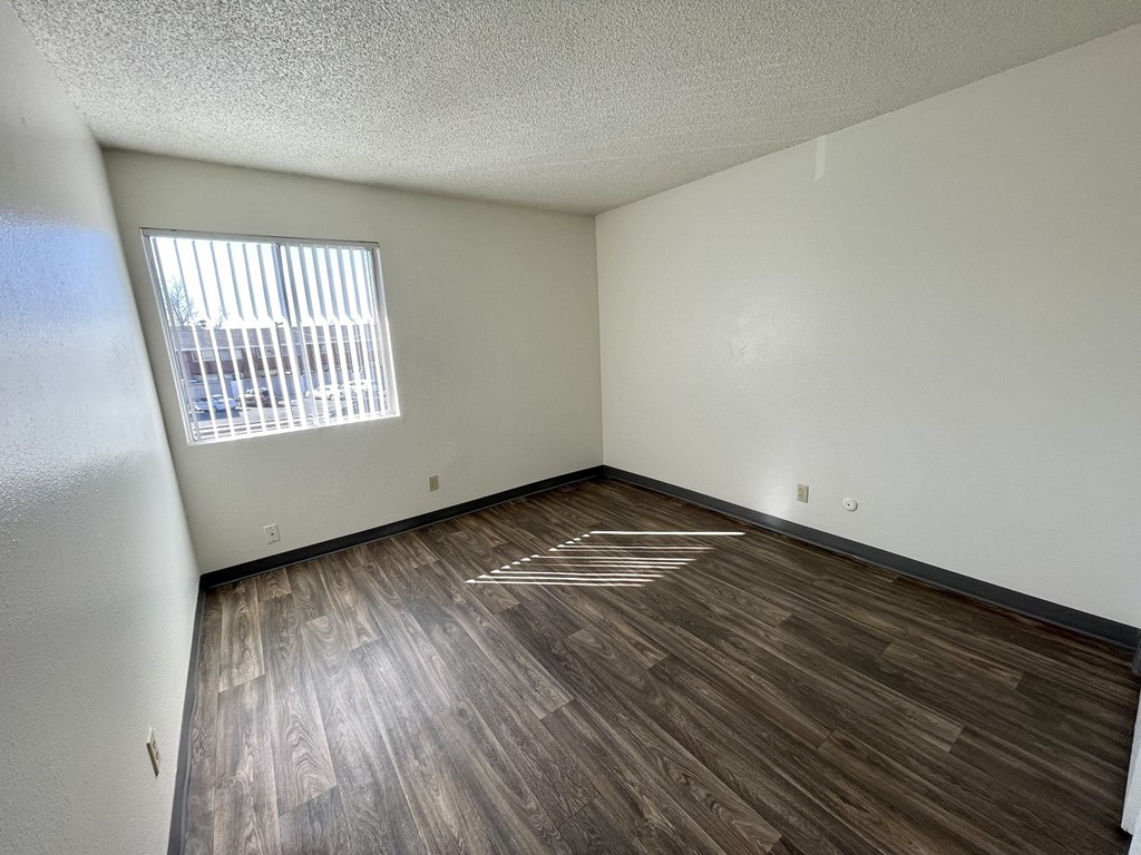 an empty living room with wood flooring and a window