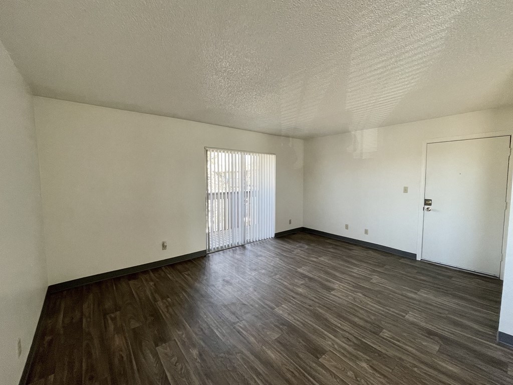 an empty living room with wood flooring and white walls