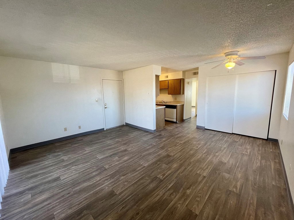 an empty living room with wood flooring and a ceiling fan