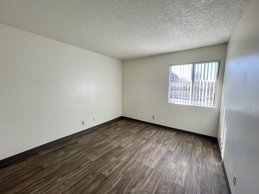 an empty living room with wood flooring and a window