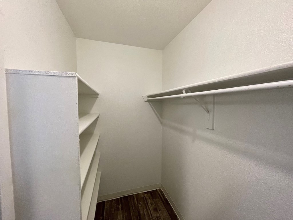 a walk in closet in an empty room with a white wall and a white closet