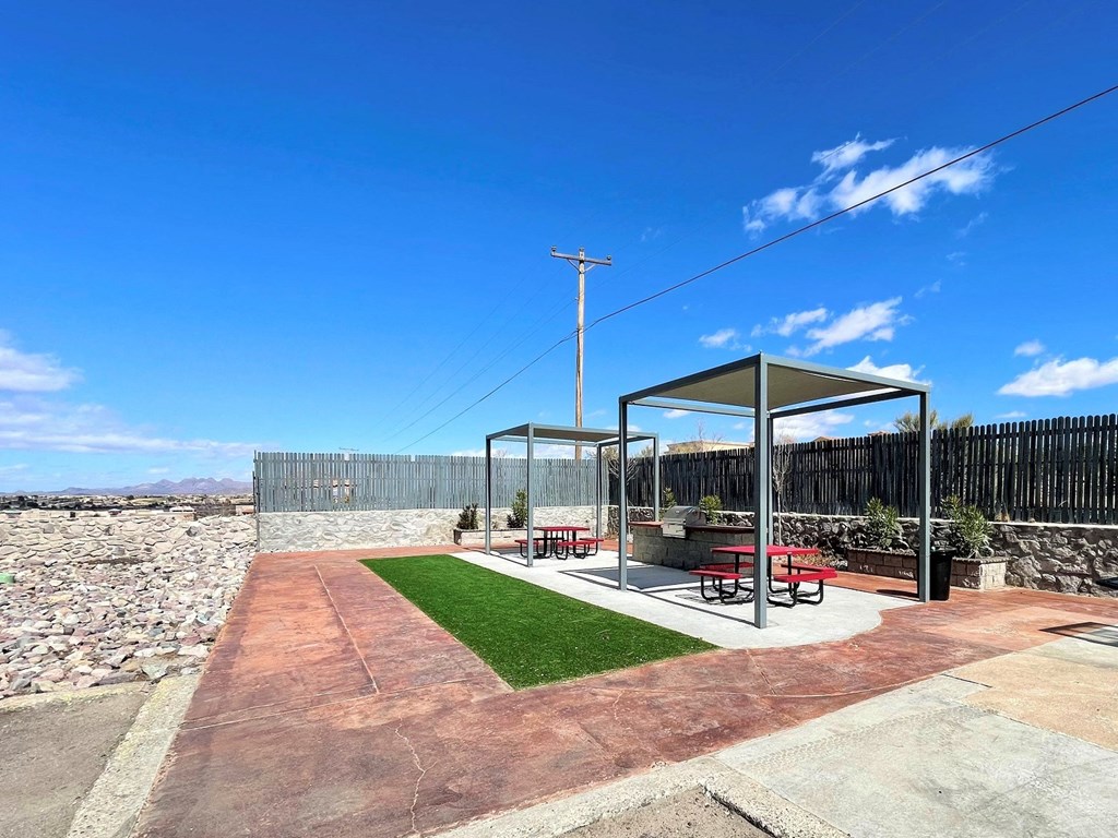 a patio with a picnic table and grass