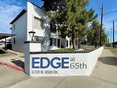 a sign that says edge at 65th in front of a white house