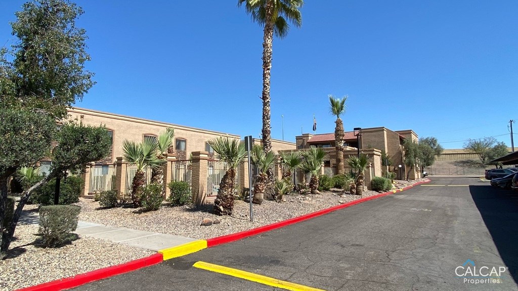 an empty street in front of a building with palm trees