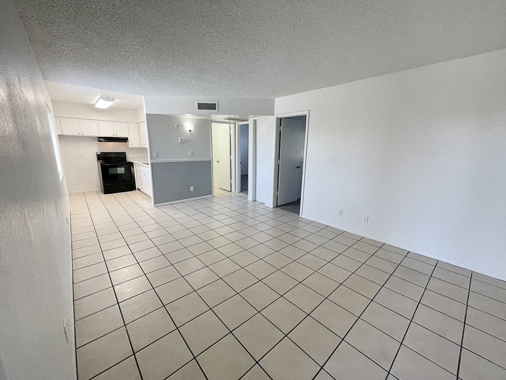 the living room and kitchen of an empty apartment with a tiled floor