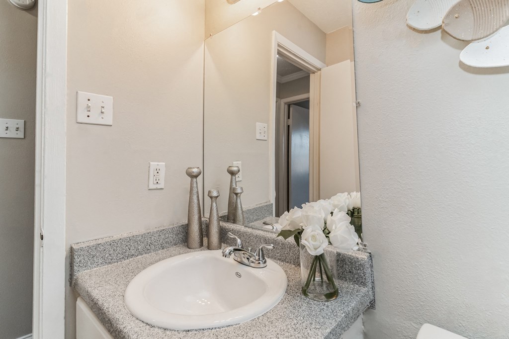 a bathroom with a sink and a mirror and a vase of flowers
