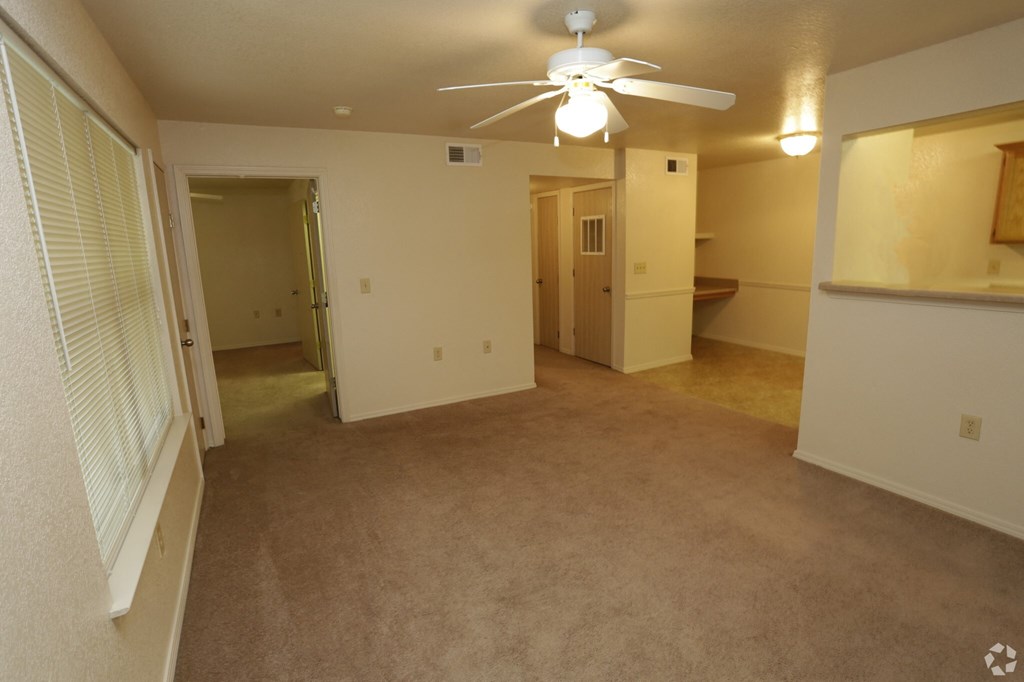 an empty living room with a ceiling fan