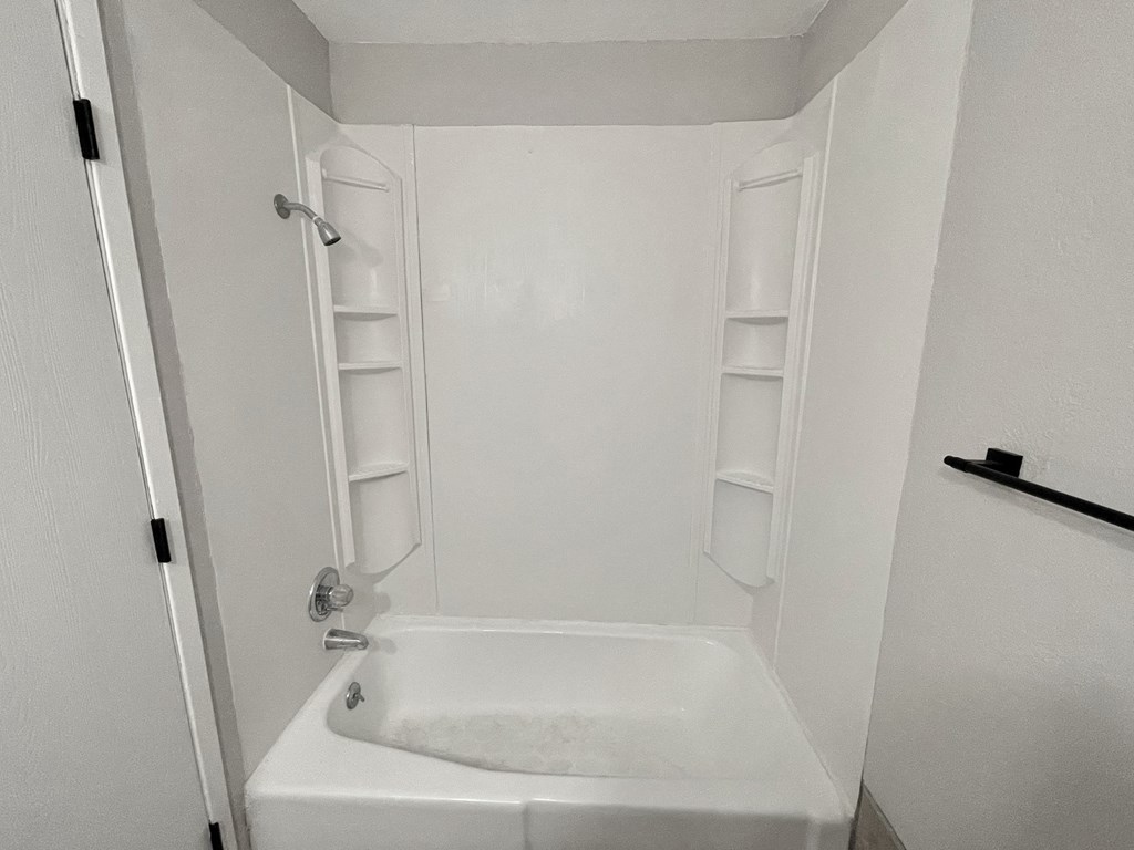 a small white bathroom with a shower and a sink