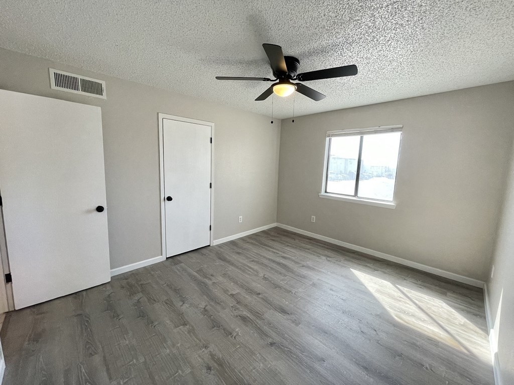an empty living room with a ceiling fan and a window